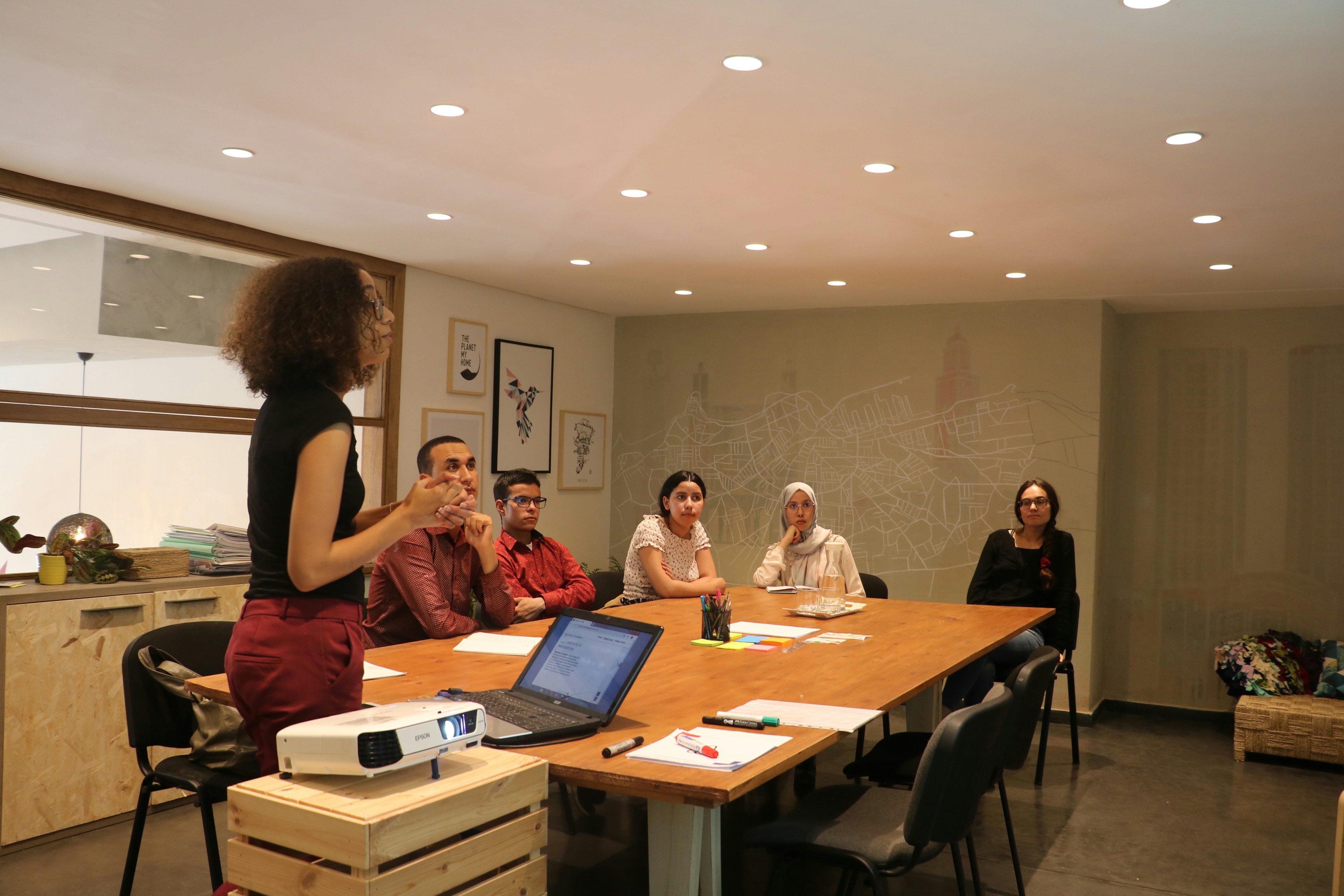 A facilitator standing during a team meeting in a workplace setting