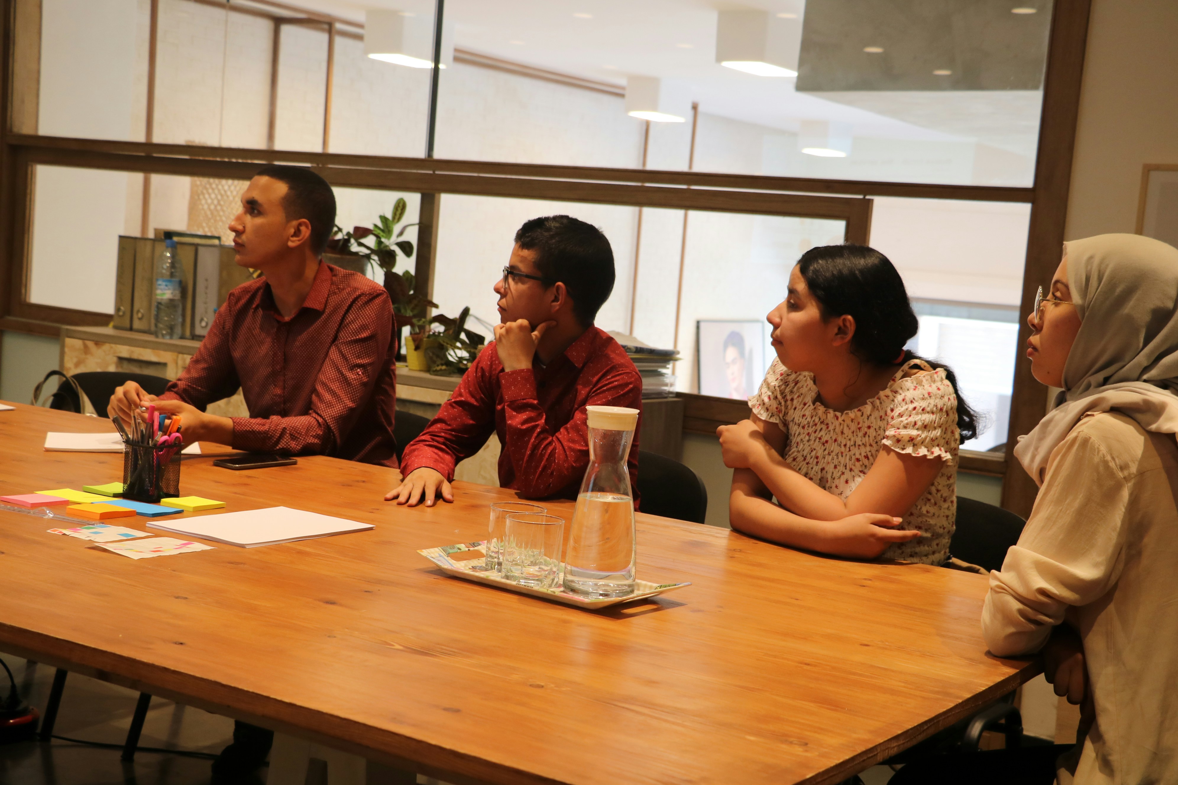 A group of young students gathered around a table, discussing together